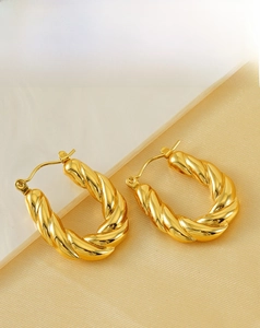 Macro view of gold plated croissant hoop earrings showing thick twisted texture detail