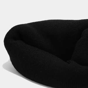Close-up of black ribbed knit beanie showing thick texture and fine stitching detail