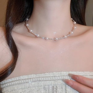 Close-up of elegant silver necklace featuring pearls and sparkling rhinestones on neck