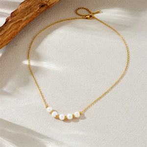 Irregular pearl and gold bead stainless steel chain necklace on a natural wood base