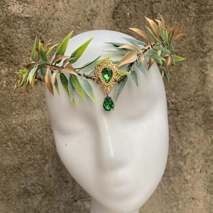 Close-up of golden leaf headpiece with green gemstones and vintage forehead pendant