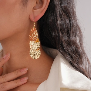 Détail de boucles d'oreilles goutte d'or à plusieurs couches avec texture martelée