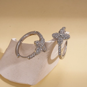 Silver geometric flower hoop earrings with zircon pavé stones on a stone prop