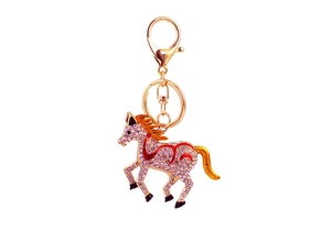 Close-up of golden horse keychain with sparkling crystals and red enamel details