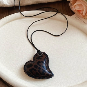 Close-up of heart-shaped leopard print pendant necklace with fine stitching detail