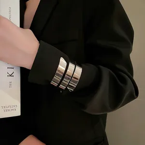 Bracciale rigido geometrico argento multistrato indossato su una manica di abito nero