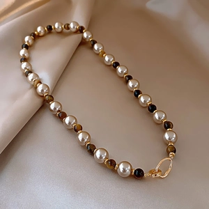Elegant pearl and tiger eye stone beaded necklace with gold accents on silk fabric
