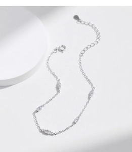 Detail of s925 silver four-leaf clover bracelet with sparkling diamonds on white surface