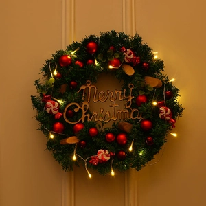 Green Christmas wreath with LED lights, red balls, pine cones and Merry Christmas sign