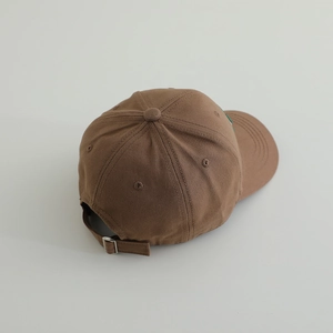 Close-up of brown cotton baseball cap showing adjustable silver metal slide buckle