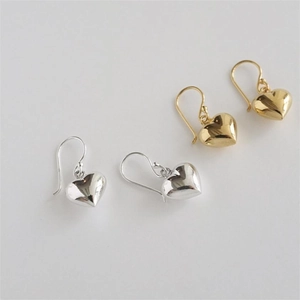 Flat lay of heart pendant earrings in silver and gold finishes with fish hook design