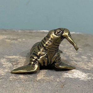 Detalle macro de estatuilla de morsa de cobre sólido con pátina vintage y colmillos reales