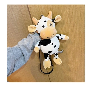 Detail of cute cow plush crossbody bag with yellow horns and black strap for children
