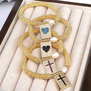 Detailed shot of gold beaded bracelets featuring zircon hearts, crosses and pearls