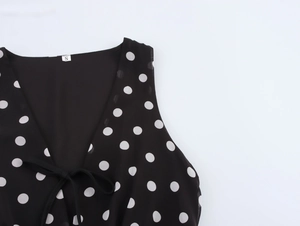 Détail de l'encolure en V avec nœud et motif à pois sur la robe en mousseline