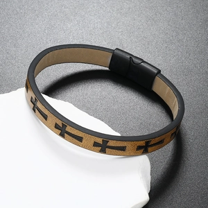 Detail of men's brown braided leather bracelet with black cross and magnetic clasp