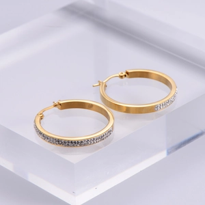 Elegant gold-plated hoop earrings with sparkling rhinestones on an acrylic stand