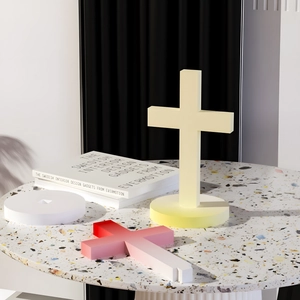 Adornos de mesa en forma de cruz de resina amarilla y rosa sobre mesa de terrazo