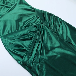 Detailaufnahme des smaragdgrünen Satinkleides mit geraffter Taille und Schlitz am Seitenteil