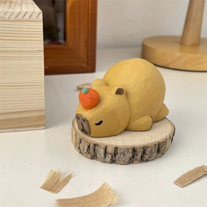 Macro shot of hand-carved wooden capybara ornament with an orange on top on a wood base