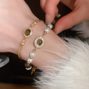 Détail d'un ensemble de bracelets dorés vintage avec perles, œil de tigre et cristaux brillants