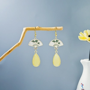 Detail of vintage bamboo leaf earrings with gold hooks and yellow resin pendants