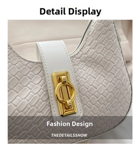 Close-up of the cream crescent bag with woven texture and a gold metal ring lock