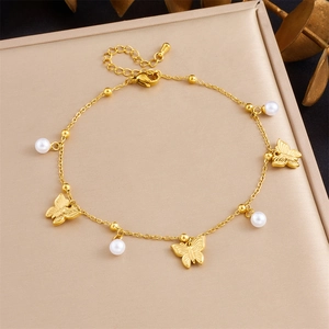 Detail of gold butterfly charms and white pearls on a stainless steel beach anklet