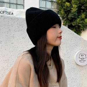 Side view of a woman wearing a thick black rabbit fur knit beanie for winter warmth