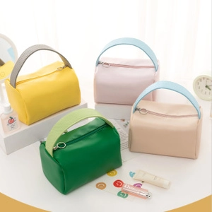 Multiple colors of handheld toiletry bags with metal ring zippers and wide handles