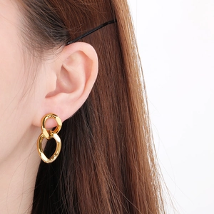 Close-up of elegant gold twisted Cuban chain earrings worn on model's ear
