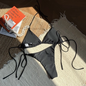 Flat lay detail of black string bikini set with 82% polyester and 18% spandex labels
