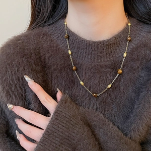 Detail of vintage tiger eye stone pendant necklace on model with brown sweater