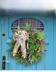 Close-up of rustic Christmas wreath with pine cones and golden bells on a blue door