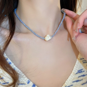 Close-up of blue beaded necklace featuring a marbled white stone heart pendant