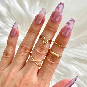 Macro shot of purple butterfly press-on nails with golden metal rings on white fur