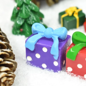 Close-up of a miniature purple resin gift box with blue bow and white polka dots