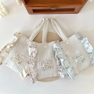 Close-up of quilted floral handbags in beige, pink, and blue with ruffle edges