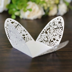 Detail of white laser-cut wedding favor box with intricate butterfly floral patterns