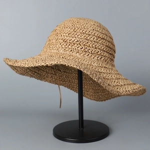 Detail of hand-woven straw hat showing fine paper fiber texture and large wavy brim