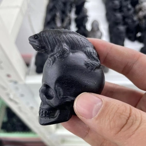 Detailed view of hand-carved matte obsidian sculpture featuring a lizard on a skull