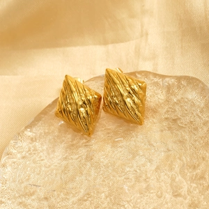 Golden rhombic stainless steel earrings with irregular texture on a silk background