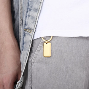 Close-up of a polished gold rectangular steel tag pendant hanging on a waistband