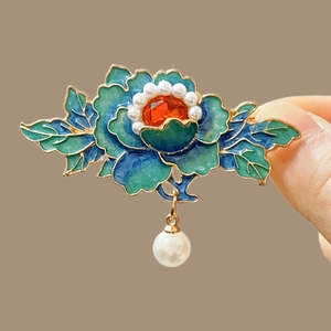 Detail of blue cloisonne flower hairpin with central red gem and elegant pearl tassel