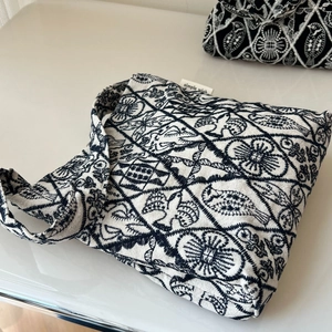 Close-up of bird and floral embroidery on a white canvas bag with a simple wish tag