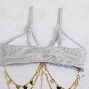 Detail of grey pleated bikini top featuring decorative gold chains and sequins over marble