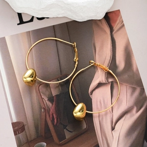 Chic gold hoop earrings with mirror-polished metallic bean drop charms on a lifestyle backdrop