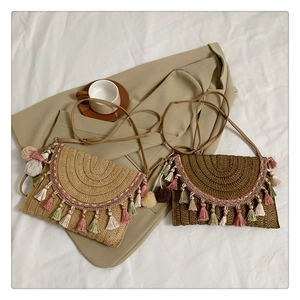Close-up of bohemian straw bags with multi-colored tassels on a soft white bed sheet