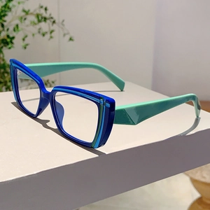 Detail of blue and green cat-eye frame glasses with polished finish on a minimalist stand