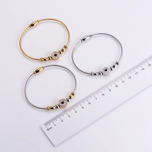 Detail of stainless steel wire rope bracelets with heart charms next to a ruler for size
